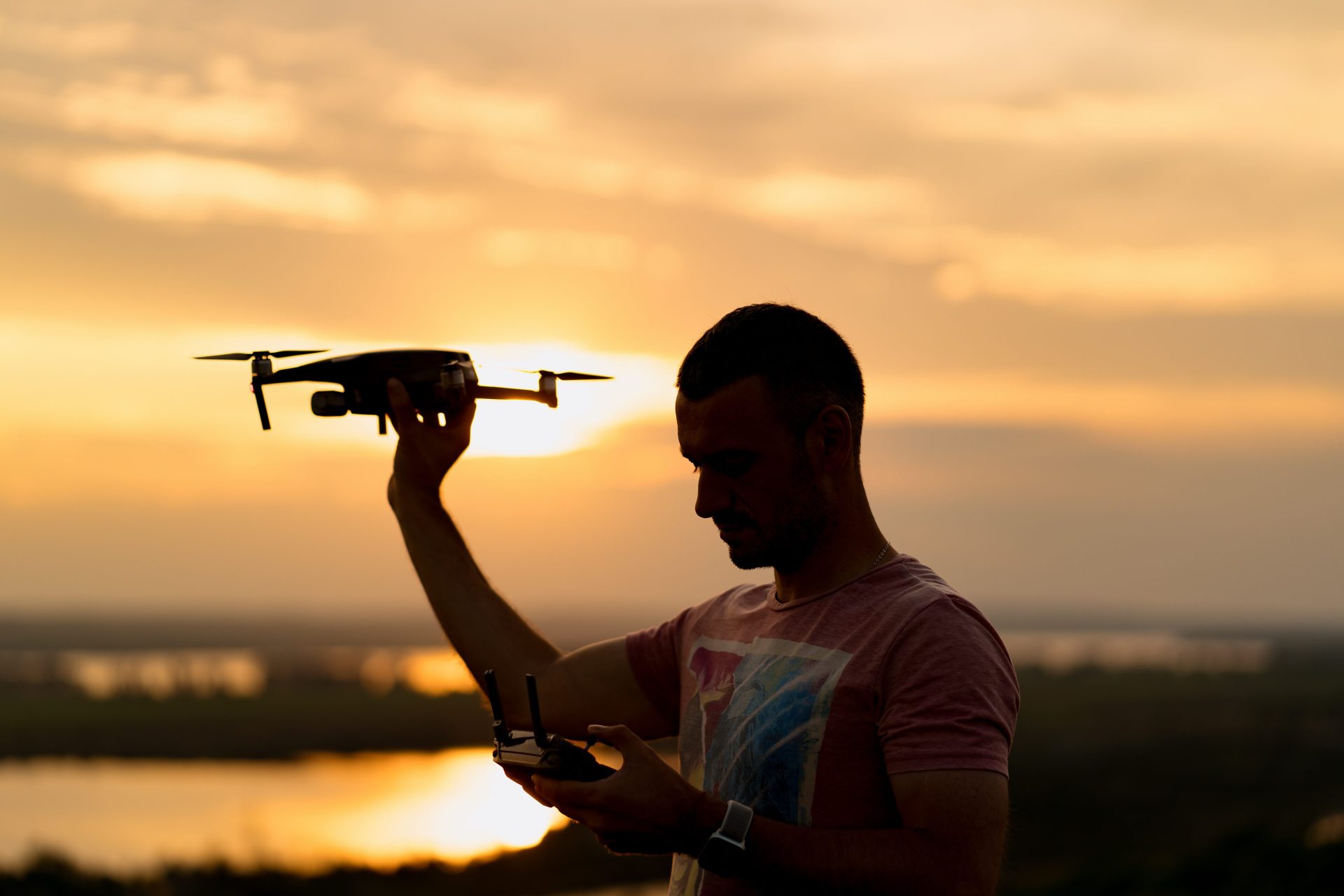silhouette man piloting drone sunset with sunny sky background
