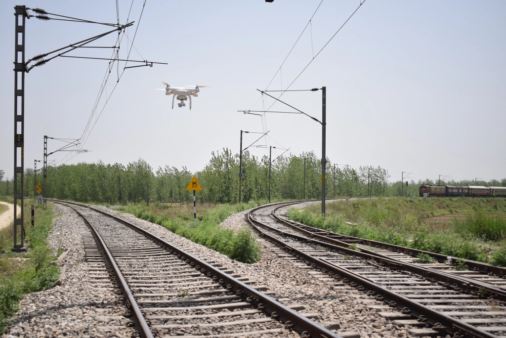 Technician inspecting overhead catenary wires on a railway line, checking for tension and alignment.
