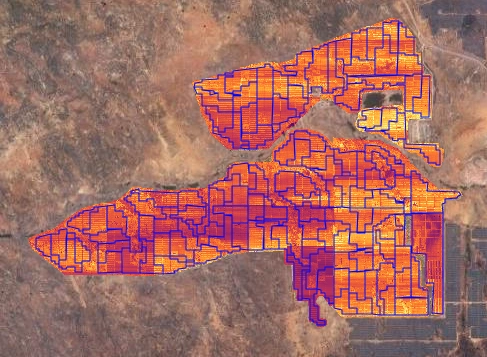 Drone-captured thermal image of ground-mounted solar panels showing temperature differences and hot spots during inspection.