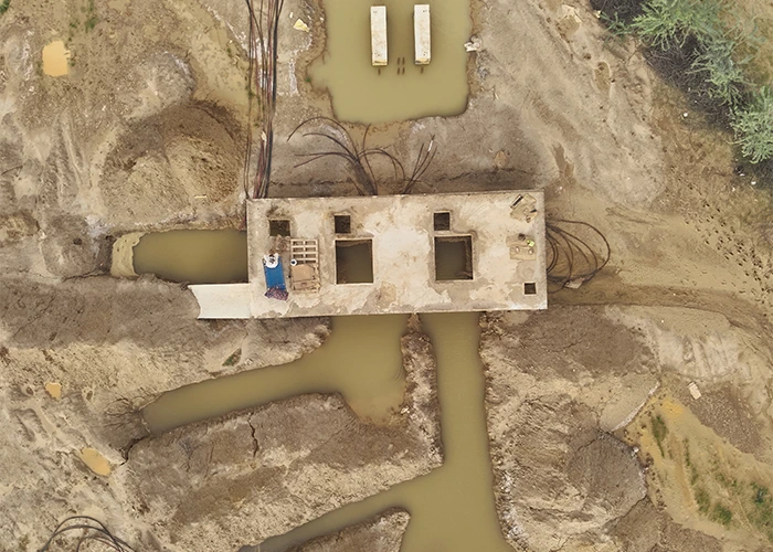 Top-down drone view of solar site civil works showing cable laying, flooded excavation trenches, and a partially constructed inverter room conditions invisible to ground-based site managers.