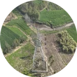 Front view drone inspection of transmission tower in farmland corridor India