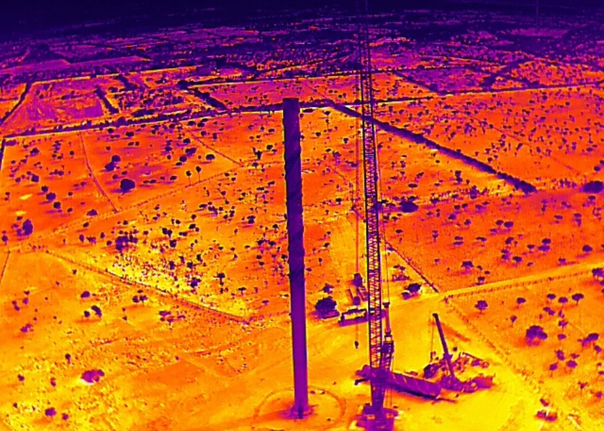 Thermal drone image of a wind turbine construction site in India showing crane operations, equipment, and surrounding land with heat mapping colors.