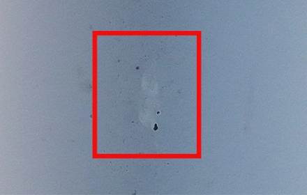 High-resolution drone photograph of wind turbine blade surface showing early-stage wearing, micro-pitting and surface degradation marked with red box during UAV inspection in India
