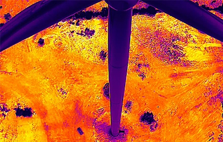 Radiometric thermal infrared drone image of wind turbine blades showing orange and yellow heat anomalies and delamination hotspots during UAV inspection in India