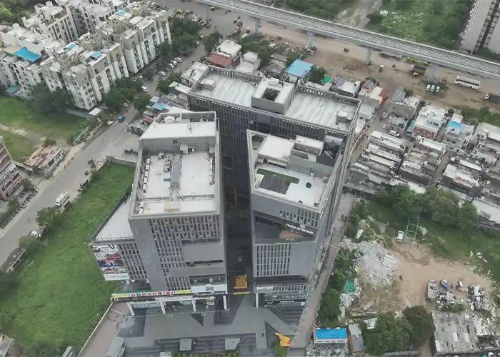 Aerial drone view of twin modern commercial high-rise towers with flat rooftops in dense urban surroundings