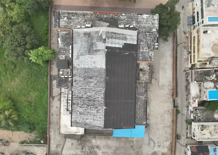 Aerial top-down drone view of commercial rooftop with partial solar panel array installed, surrounded by urban buildings