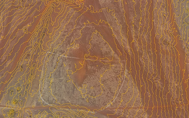 Orange contour lines overlaid on arid desert terrain orthomosaic with circular site boundary marker showing gradient variation