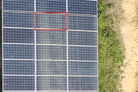 Aerial view of solar panels with visible dust and soiling streaks, one soiled module highlighted in red