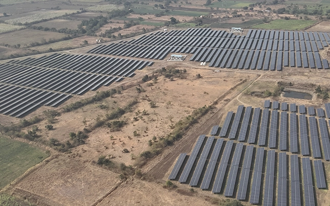 Aerial view of two ground mount solar array blocks separated by access corridor on dry terrain, with surrounding agricultural fields
