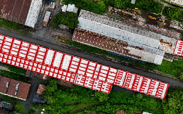 Drone orthomosaic of industrial rooftop complex with red solar panel array boundary annotations overlaid across multiple roof sections