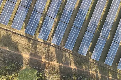 Aerial view of solar farm rows with diagonal shadow shading cast across multiple panel strings