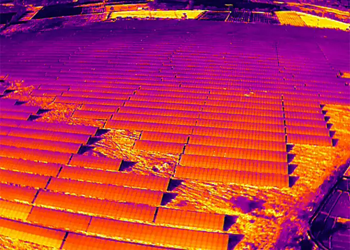 Thermal image of solar panels showing two bright orange-yellow hotspot zones indicating multi-module thermal anomalies across the array