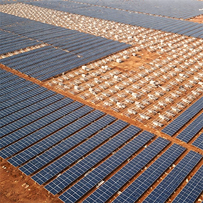 Aerial view of utility-scale solar farm with dense panel rows and equipment structures on red earth terrain