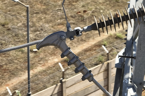 Close-up of an arcing horn and clamp hardware attached to a transmission line insulator