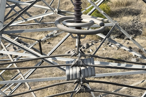 Corona control rings and connected hardware viewed from above at transmission tower peak