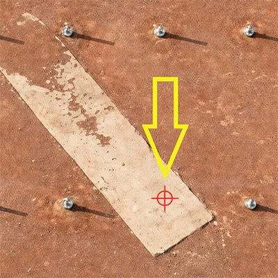 Close-up of concrete strip with bolts, yellow arrow and red crosshair marking a specific inspection point