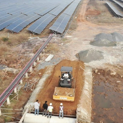 Aerial view of construction rail track and workers with compactor machine beside solar panel rows
