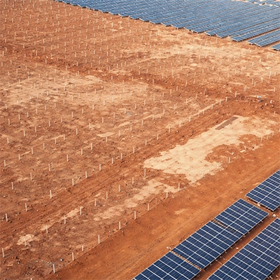 Aerial view of solar farm construction site showing grid of pile markers next to installed panel rows
