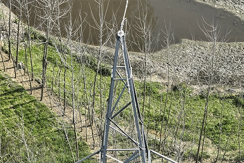 Aerial view of transmission tower apex with ground wire jumper loop above a pond