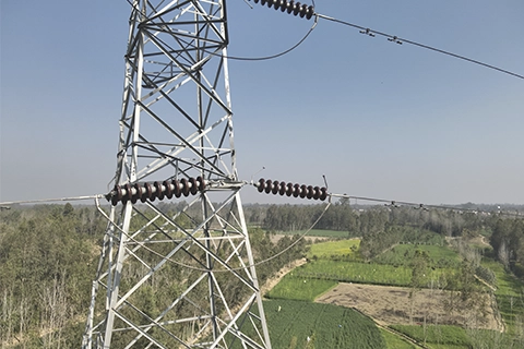 Transmission tower viewed from elevated angle showing insulator strings and conductor jumper connections